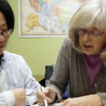 Placeholder image: a tutor pointing to a workbook beside a student.